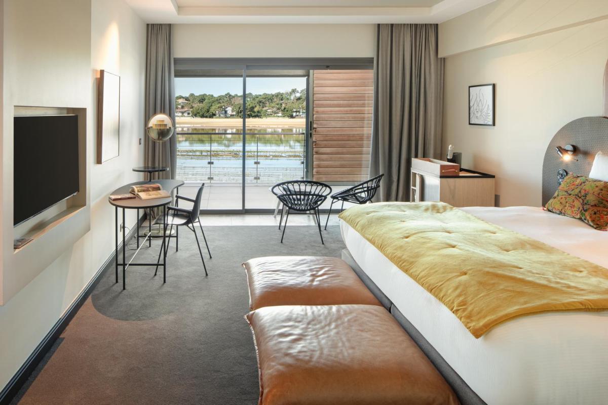 une chambre d'hôtel avec un lit, une table et des chaises dans l'établissement Hôtel & Spa Villa Seren, à Hossegor