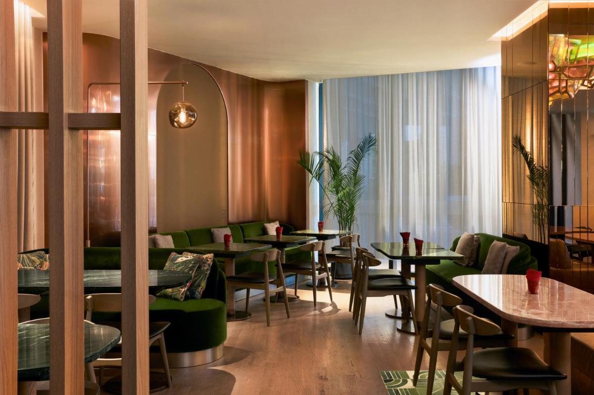 a restaurant with green tables and green chairs at Mondrian Singapore Duxton in Singapore a restaurant with green tables and green chairs at Mondrian Singapore Duxton in Singapore