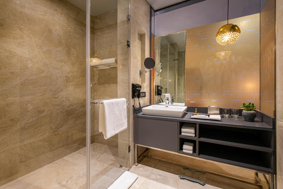 a bathroom with a sink and a mirror at Grand Mercure Bengaluru at Gopalan Mall - An Accor Brand in Bengaluru a bathroom with a sink and a mirror at Grand Mercure Bengaluru at Gopalan Mall - An Accor Brand in Bengaluru