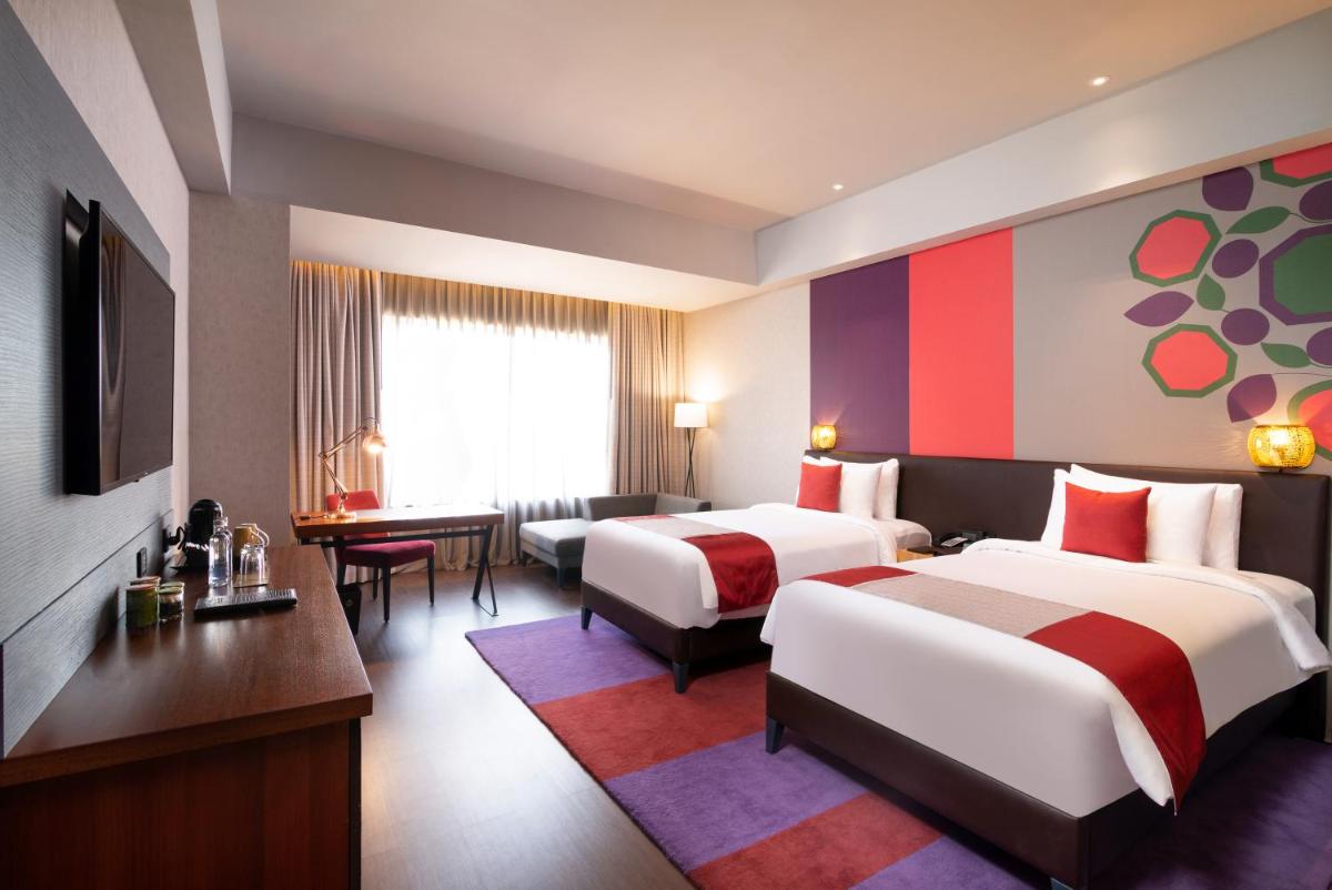 a hotel room with two beds and a desk at Grand Mercure Bengaluru at Gopalan Mall - An Accor Brand in Bengaluru a hotel room with two beds and a desk at Grand Mercure Bengaluru at Gopalan Mall - An Accor Brand in Bengaluru