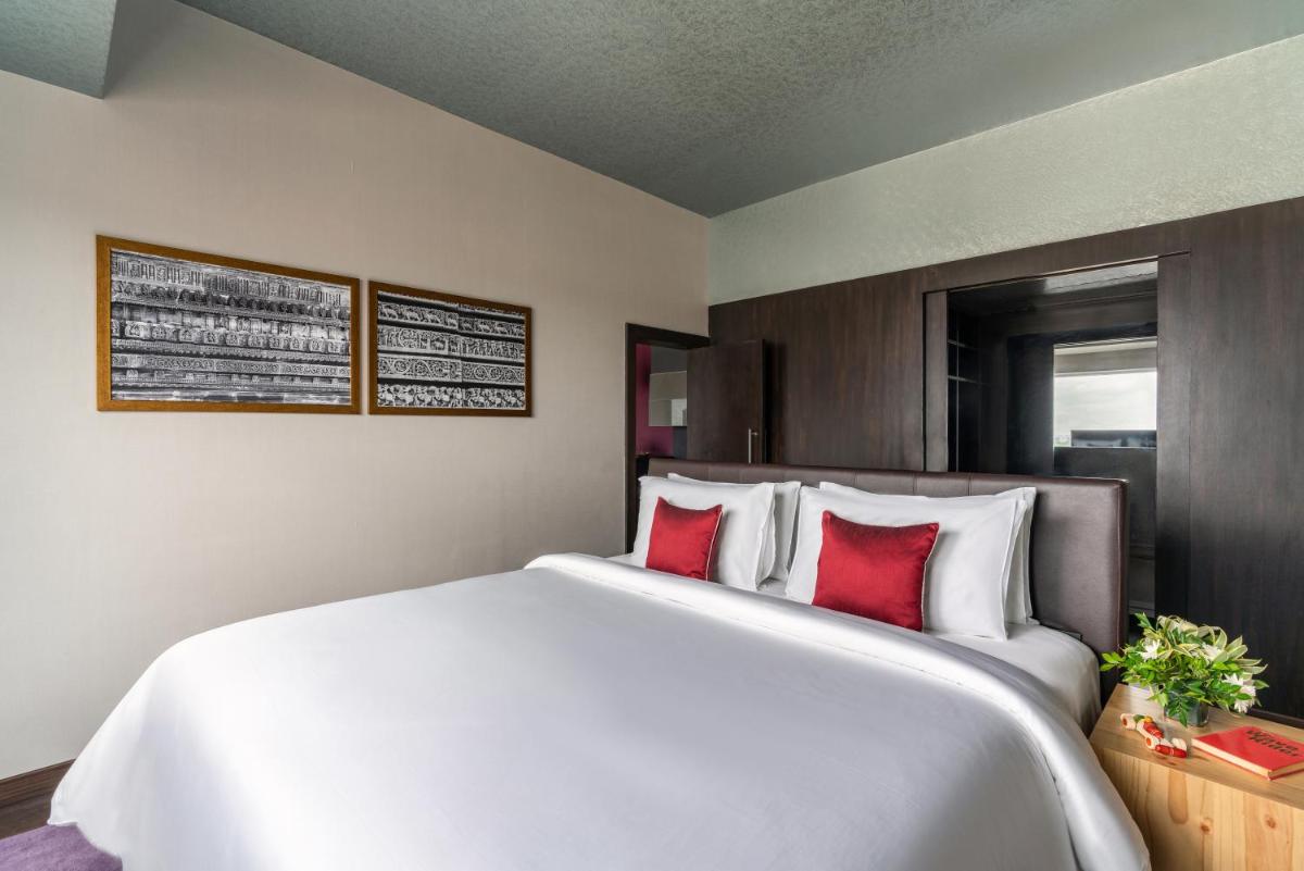 a bedroom with a large white bed with red pillows at Grand Mercure Bengaluru at Gopalan Mall - An Accor Brand in Bengaluru a bedroom with a large white bed with red pillows at Grand Mercure Bengaluru at Gopalan Mall - An Accor Brand in Bengaluru