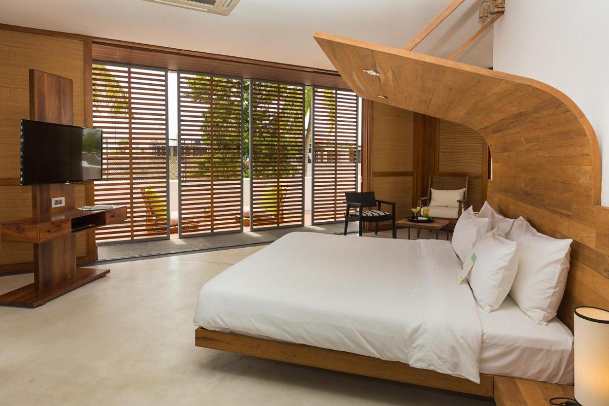 a bedroom with a large bed with a wooden headboard at La Villa in Puducherry