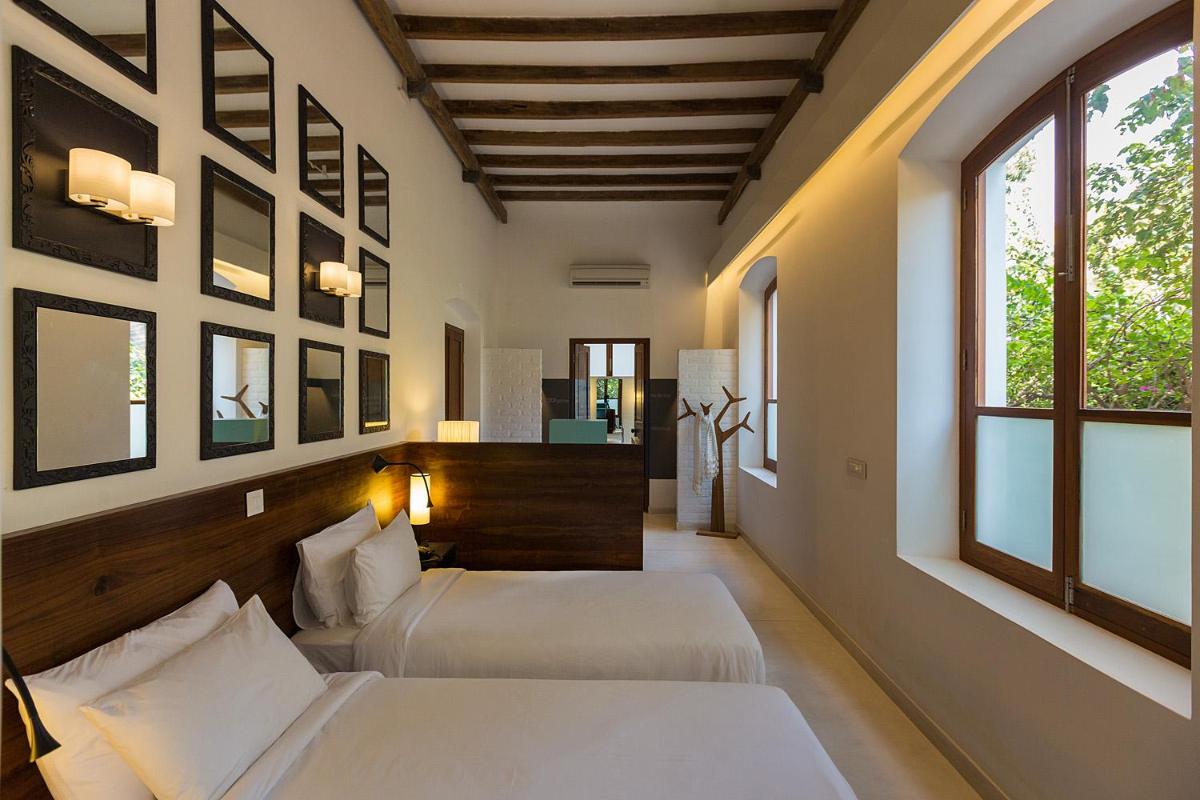 two beds in a room with two windows at La Villa in Puducherry
