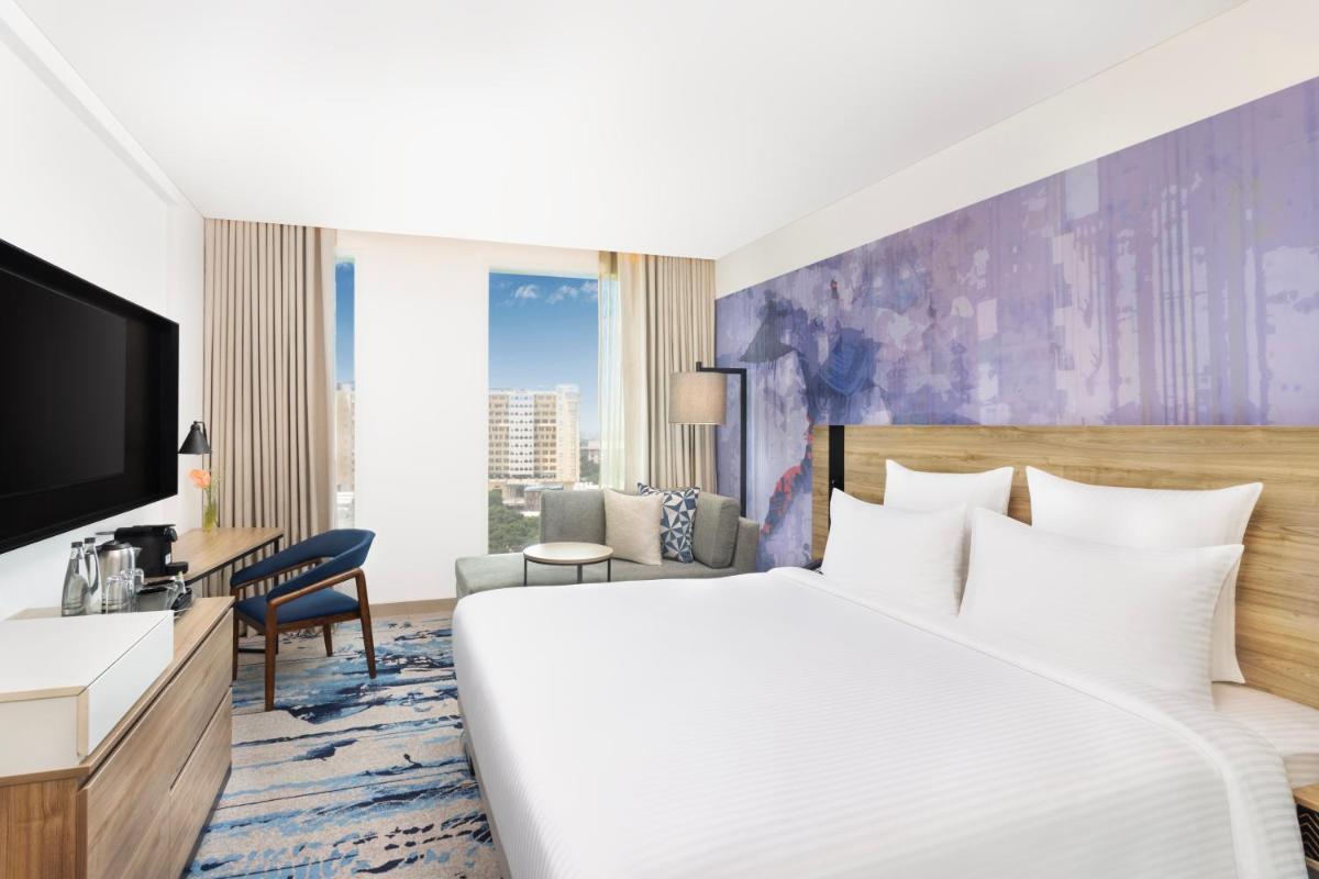 a hotel room with a bed and a tv at Novotel New Delhi City Centre in New Delhi a hotel room with a bed and a tv at Novotel New Delhi City Centre in New Delhi