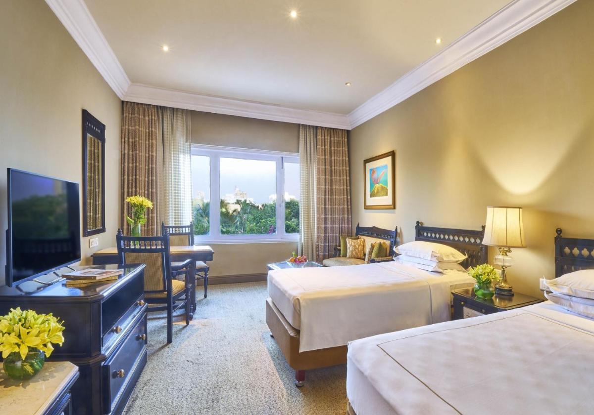 a hotel room with two beds and a desk at Taj Bengal in Kolkata