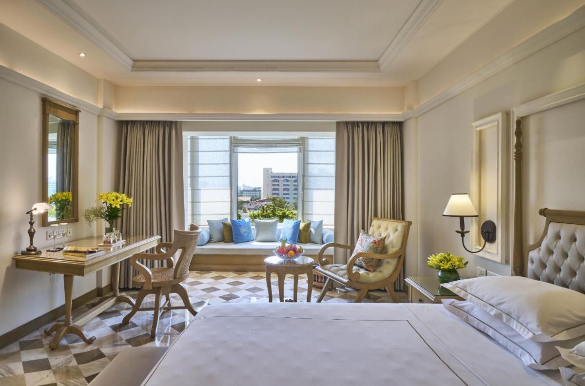 a hotel room with a bed and a desk and chairs at Taj Bengal in Kolkata
