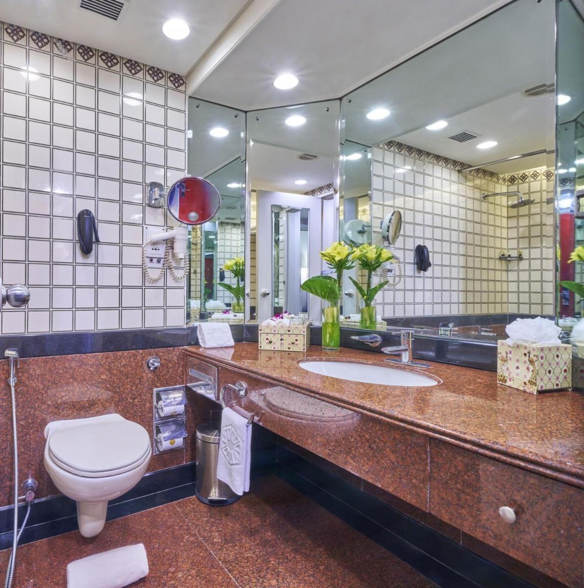 a bathroom with a toilet and a large mirror at Taj Bengal in Kolkata
