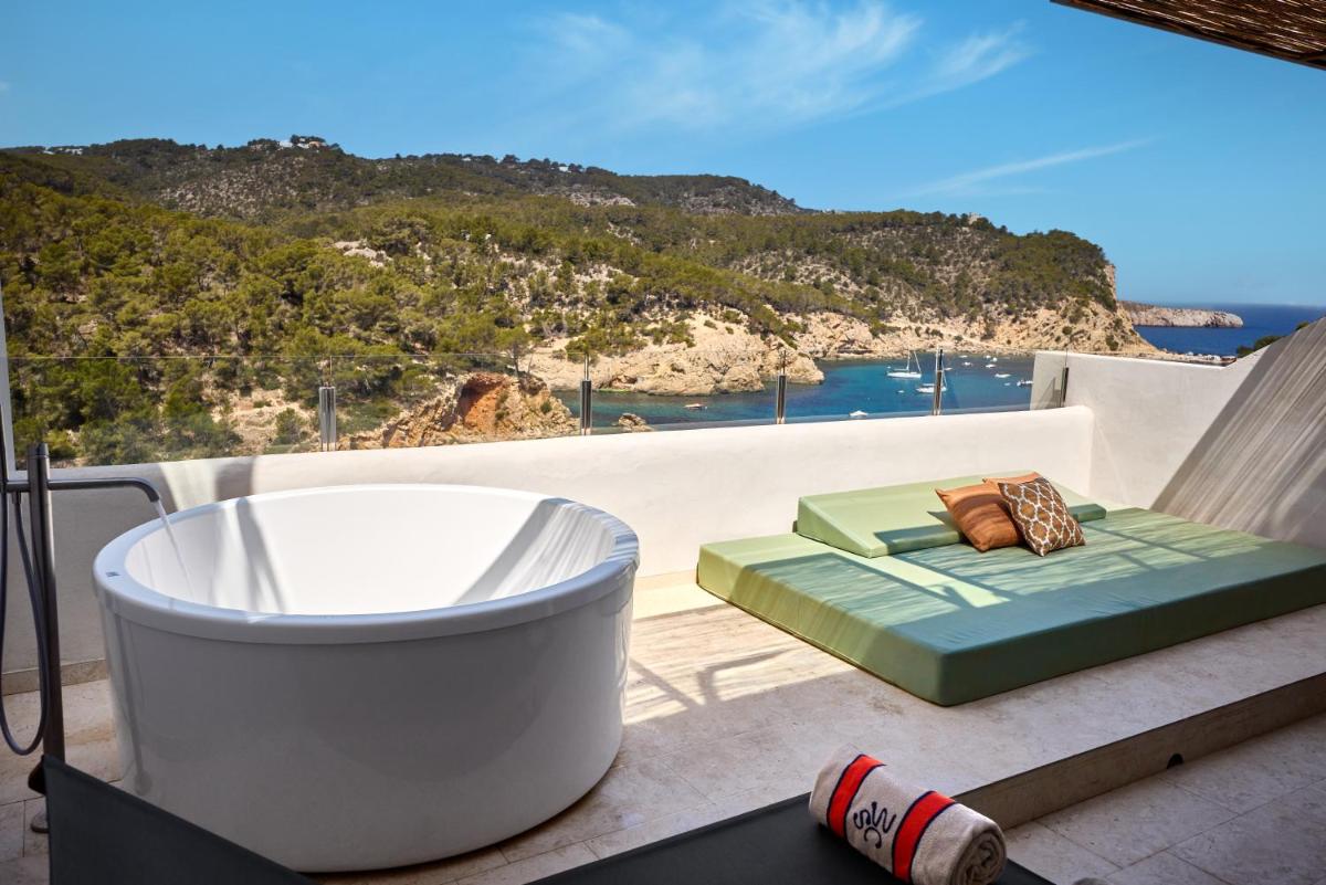Una bañera en un balcón con vista al mar. en Cala San Miguel Ibiza Resort, Adults only, Curio Collection by Hilton, en Puerto de San Miguel