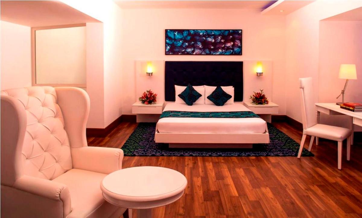 a bedroom with a bed and a chair and a table at Radisson Blu Kochi in Cochin