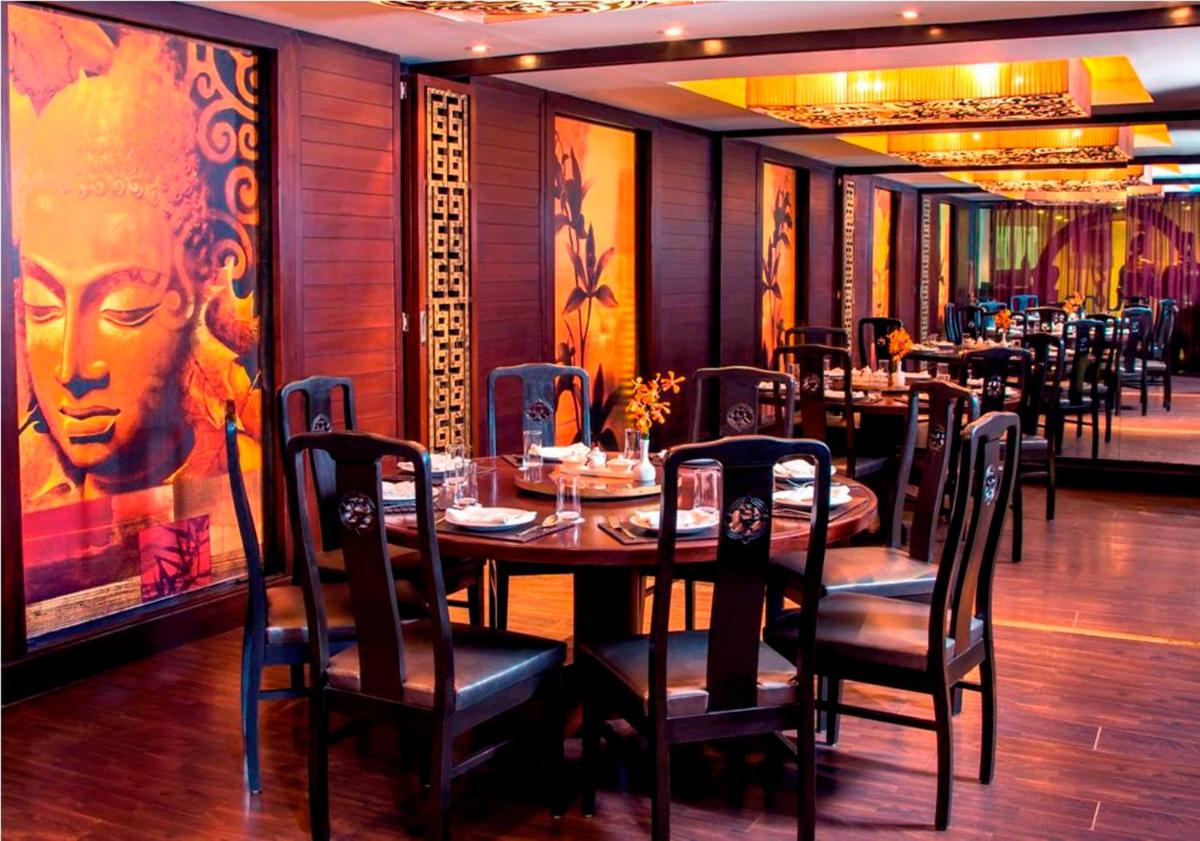a dining room with tables and chairs and a painting at Radisson Blu Kochi in Cochin