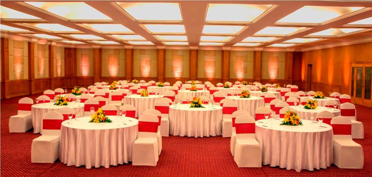 a large room with white tables and red chairs at Radisson Blu Kochi in Cochin