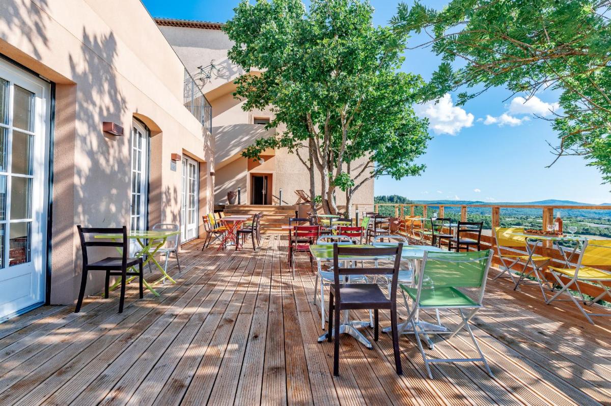 une terrasse avec tables et chaises sur une terrasse en bois dans l'établissement Le Nesk Ventoux - Hotel, à Sault