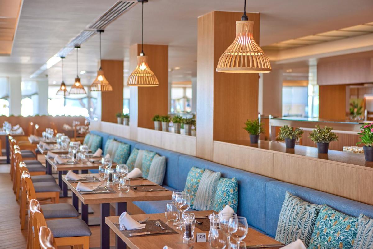 Un restaurante con mesas y sillas de madera y luces. en Universal Hotel Lido Park & Spa, en Paguera