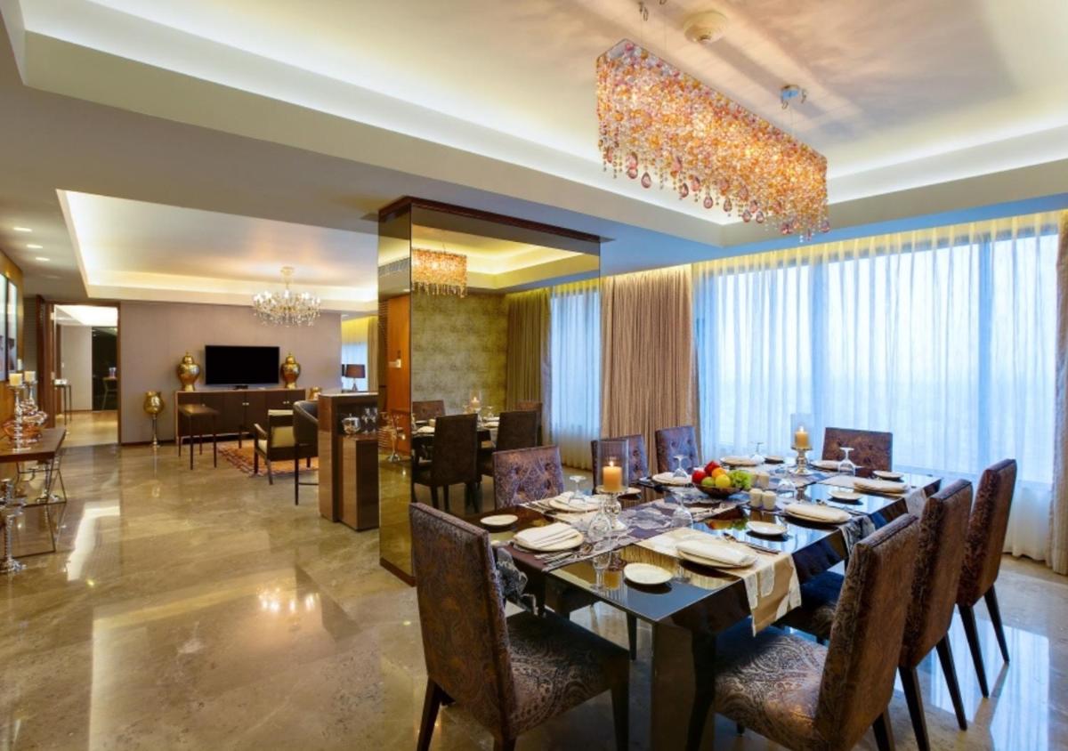 a dining room with a long table and chairs at Novotel Kolkata Hotel and Residences in Kolkata a dining room with a long table and chairs at Novotel Kolkata Hotel and Residences in Kolkata
