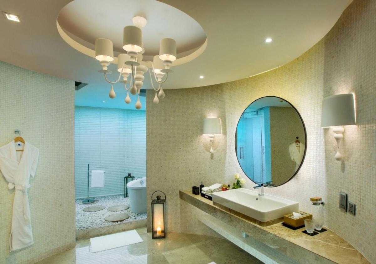 a bathroom with a sink and a mirror and a tub at Novotel Kolkata Hotel and Residences in Kolkata a bathroom with a sink and a mirror and a tub at Novotel Kolkata Hotel and Residences in Kolkata