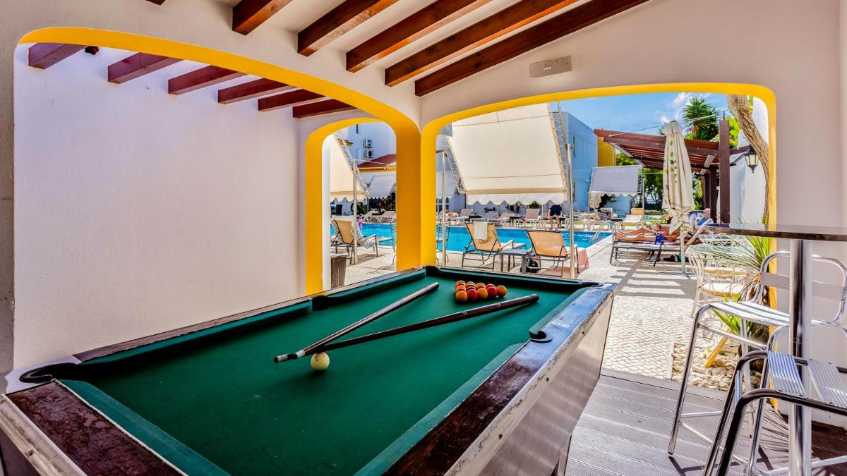 uma mesa de bilhar num quarto ao lado de uma piscina em Hotel do Cerro em Albufeira
