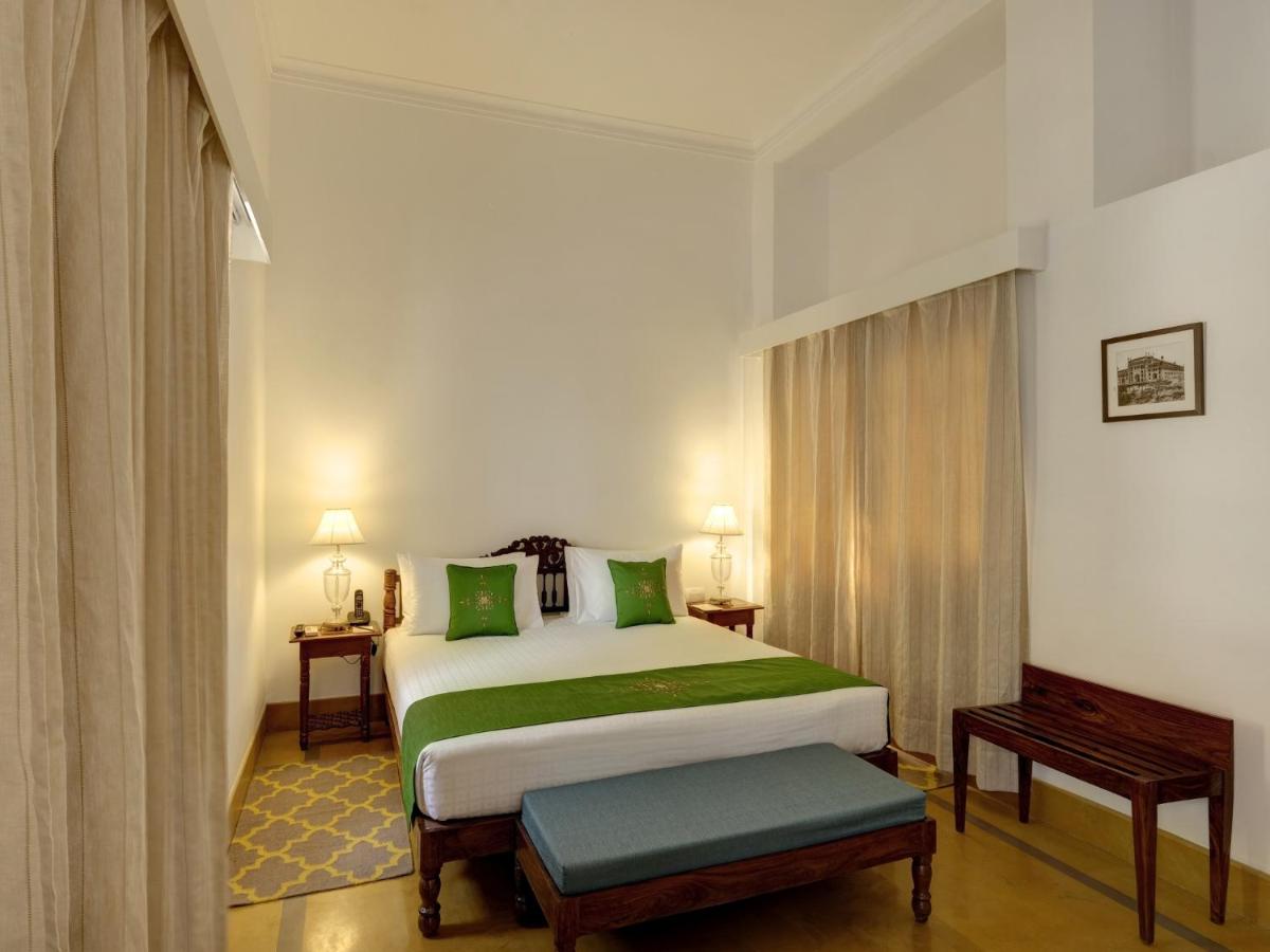 a bedroom with a large bed with green pillows at Saraca Hotel Lucknow in Lucknow