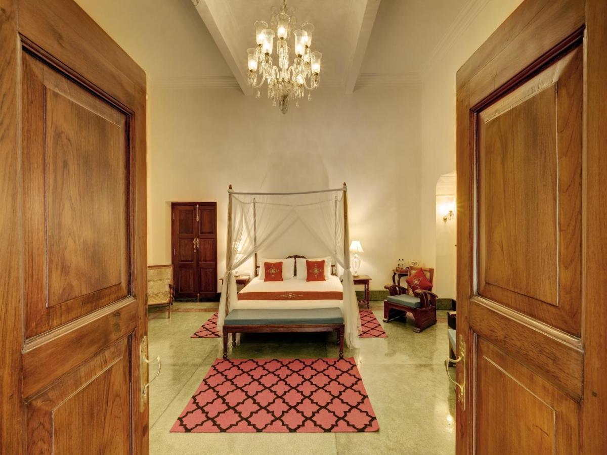 a bedroom with a bed and a chandelier at Saraca Hotel Lucknow in Lucknow