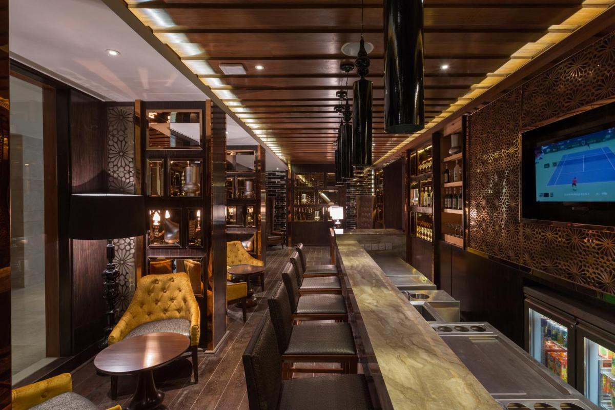 a bar with couches and a tv on a wall at Holiday Inn Jaipur City Centre by IHG in Jaipur a bar with couches and a tv on a wall at Holiday Inn Jaipur City Centre by IHG in Jaipur