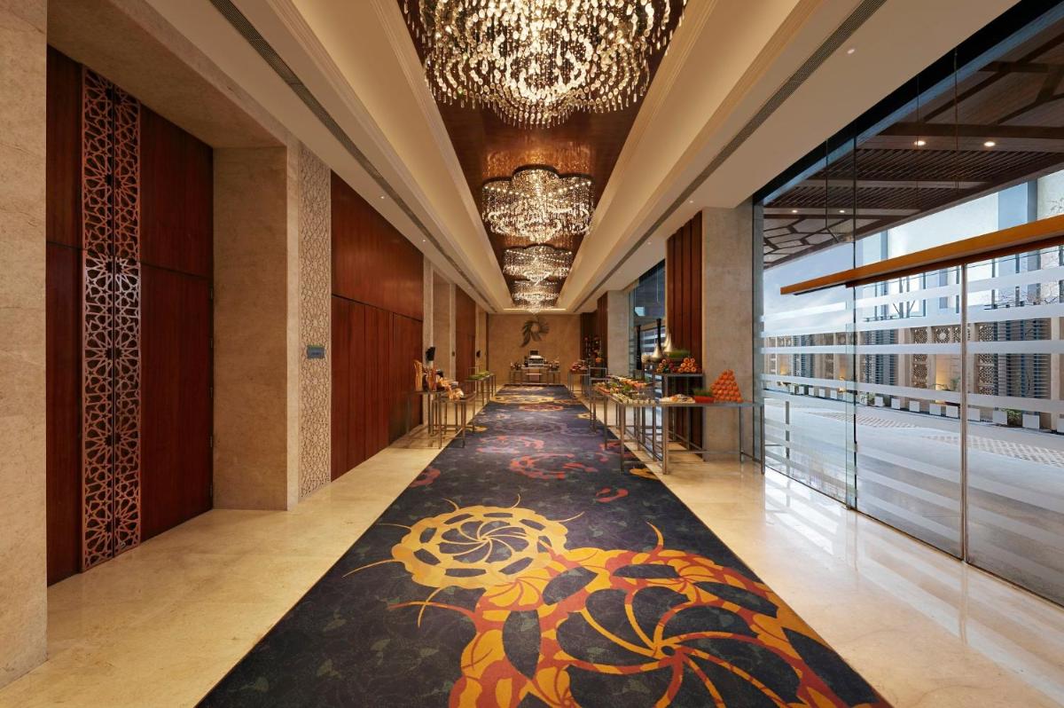 a hallway with a carpet in the middle of a building at Holiday Inn Jaipur City Centre by IHG in Jaipur a hallway with a carpet in the middle of a building at Holiday Inn Jaipur City Centre by IHG in Jaipur