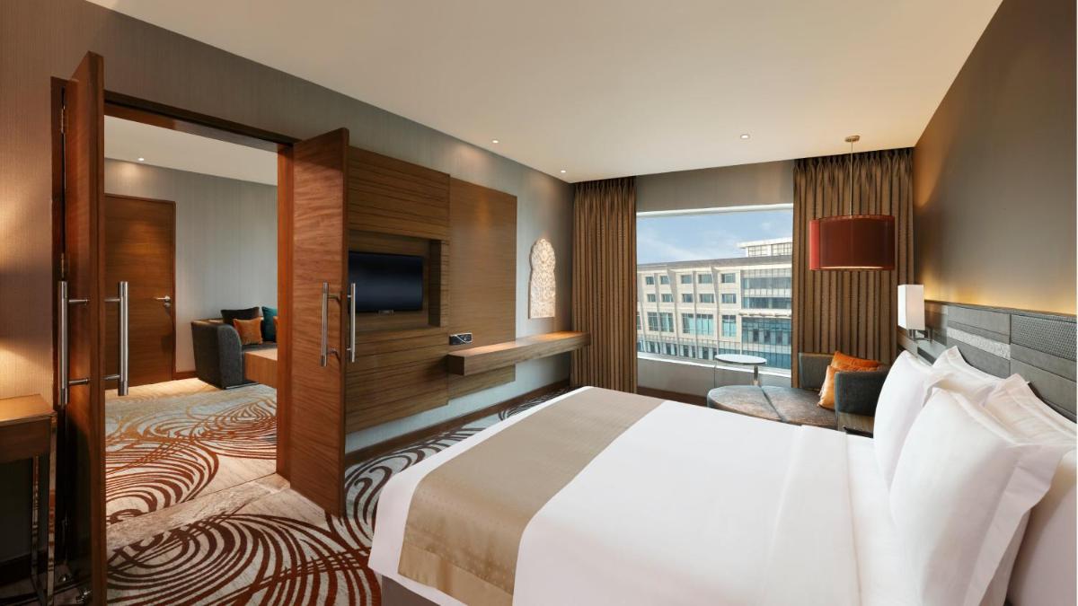 a hotel room with a bed and a flat screen tv at Holiday Inn Jaipur City Centre by IHG in Jaipur a hotel room with a bed and a flat screen tv at Holiday Inn Jaipur City Centre by IHG in Jaipur