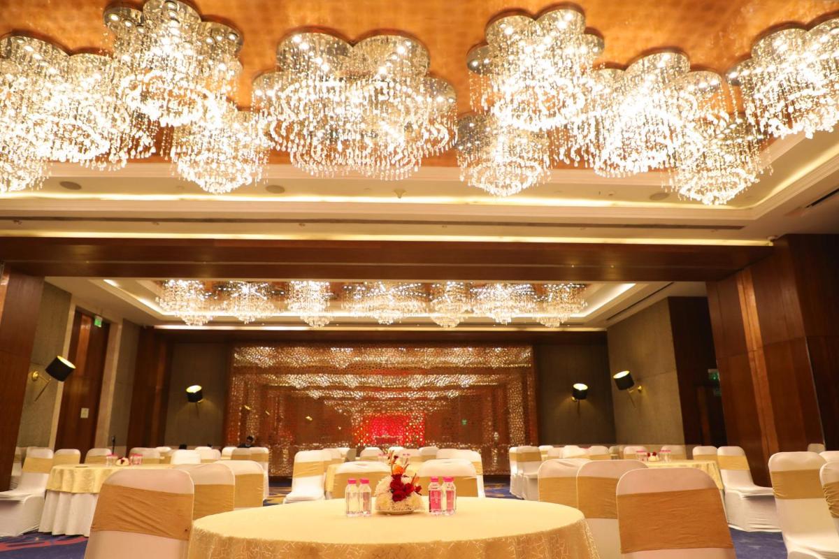 a banquet hall with white chairs and chandeliers at Holiday Inn Jaipur City Centre by IHG in Jaipur a banquet hall with white chairs and chandeliers at Holiday Inn Jaipur City Centre by IHG in Jaipur