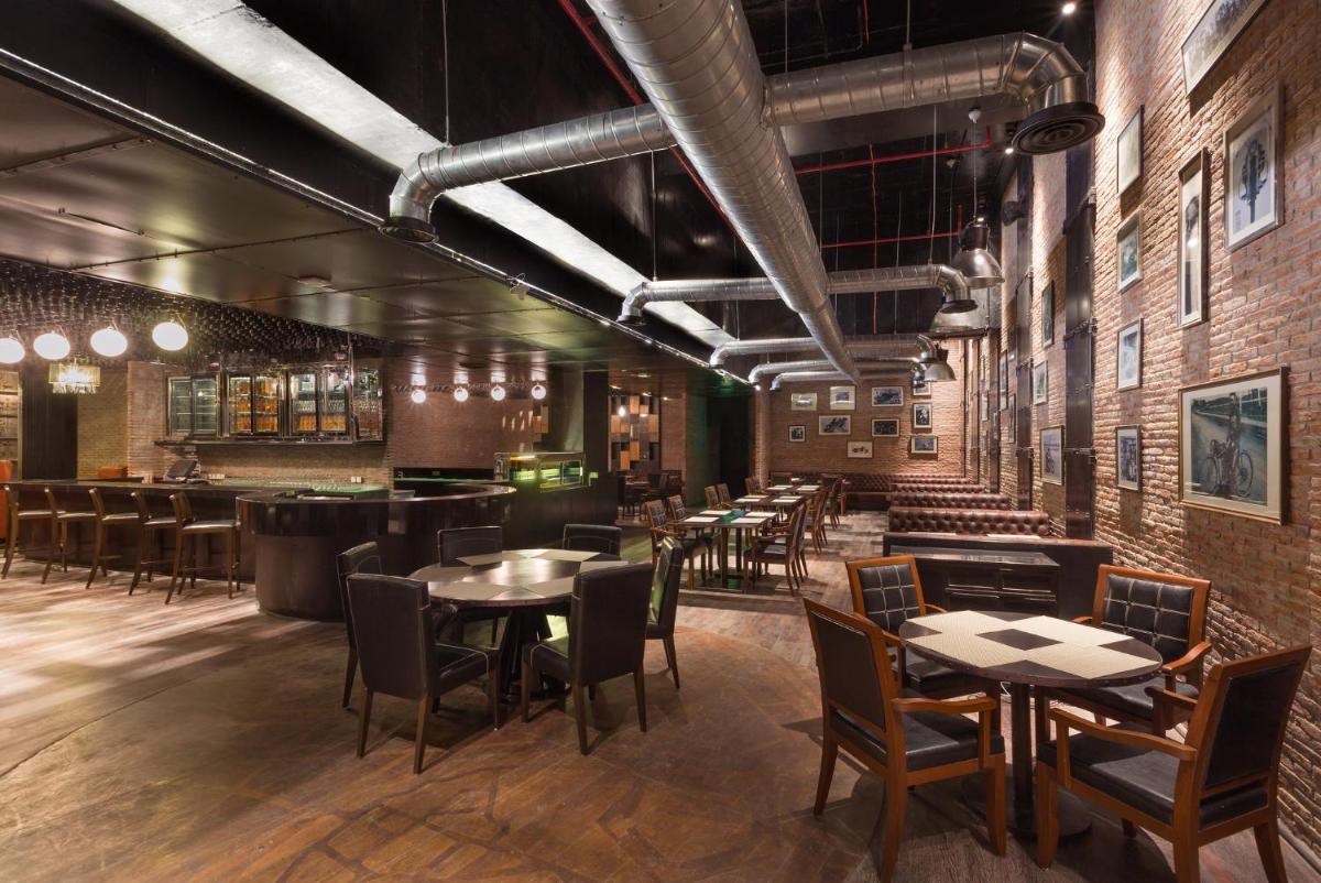 a restaurant with tables and chairs and a bar at Holiday Inn Jaipur City Centre by IHG in Jaipur a restaurant with tables and chairs and a bar at Holiday Inn Jaipur City Centre by IHG in Jaipur