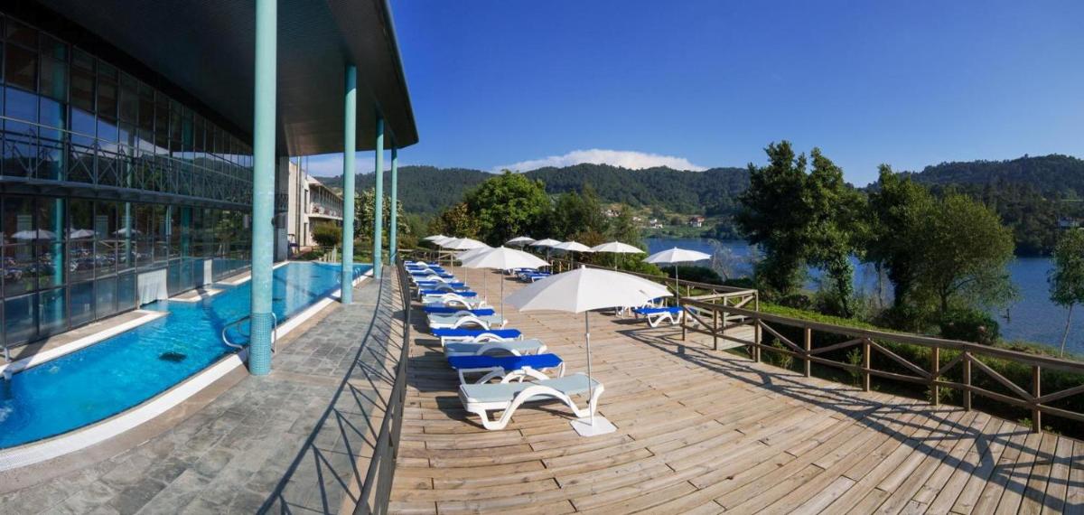 una piscina con tumbonas y sombrillas junto a un edificio en Laias Caldaria hotel y Balneario, en Laias