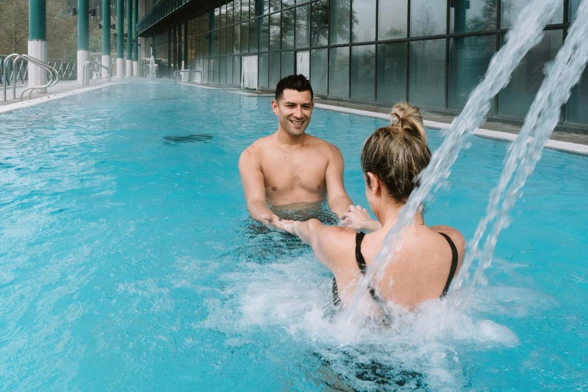 un hombre y una mujer en una piscina en Laias Caldaria hotel y Balneario, en Laias