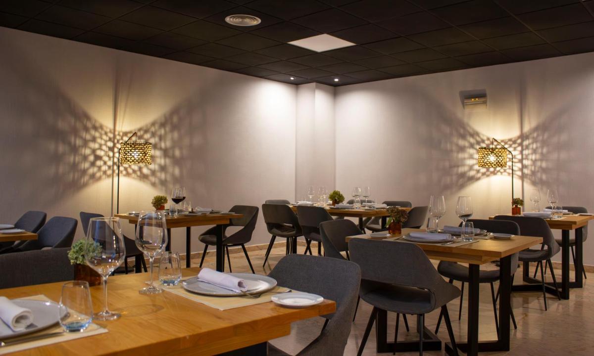 Un comedor con mesas, sillas y luces. en Laias Caldaria hotel y Balneario, en Laias