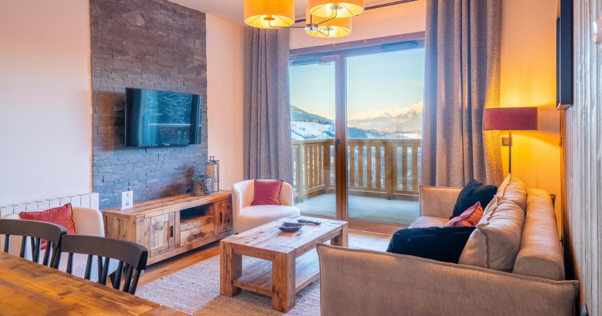 un salon avec un canapé, une télévision et une table dans l'établissement Résidence l'Ecrin d'Argent by My Mountain Resort, à Valmorel