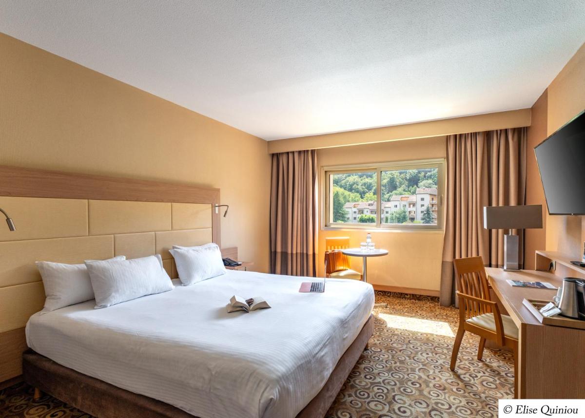 une chambre d'hôtel avec un grand lit et un bureau dans l'établissement Hôtel Lyon Métropole & Spa, à Lyon