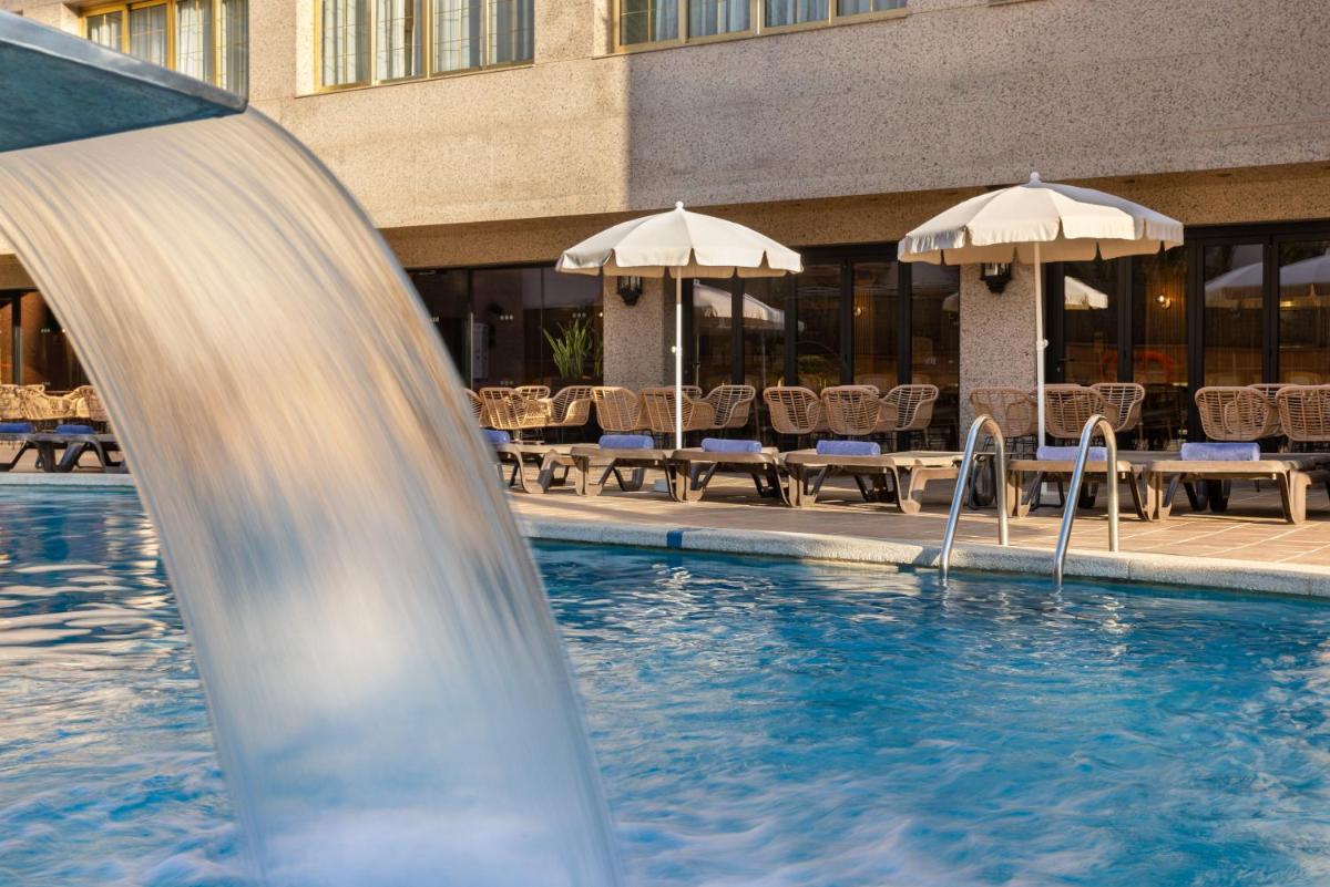 un tobogán de agua en una piscina con sillas y sombrillas en htop Amaika & SPA 4Sup - Adults Only #htopBliss, en Calella