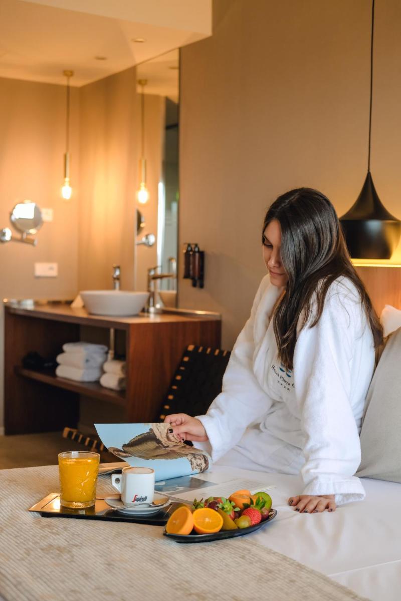 una mujer sentada en una habitación de hotel con una bandeja de comida en Hotel Playa Golf - Adults Only, en Playa de Palma