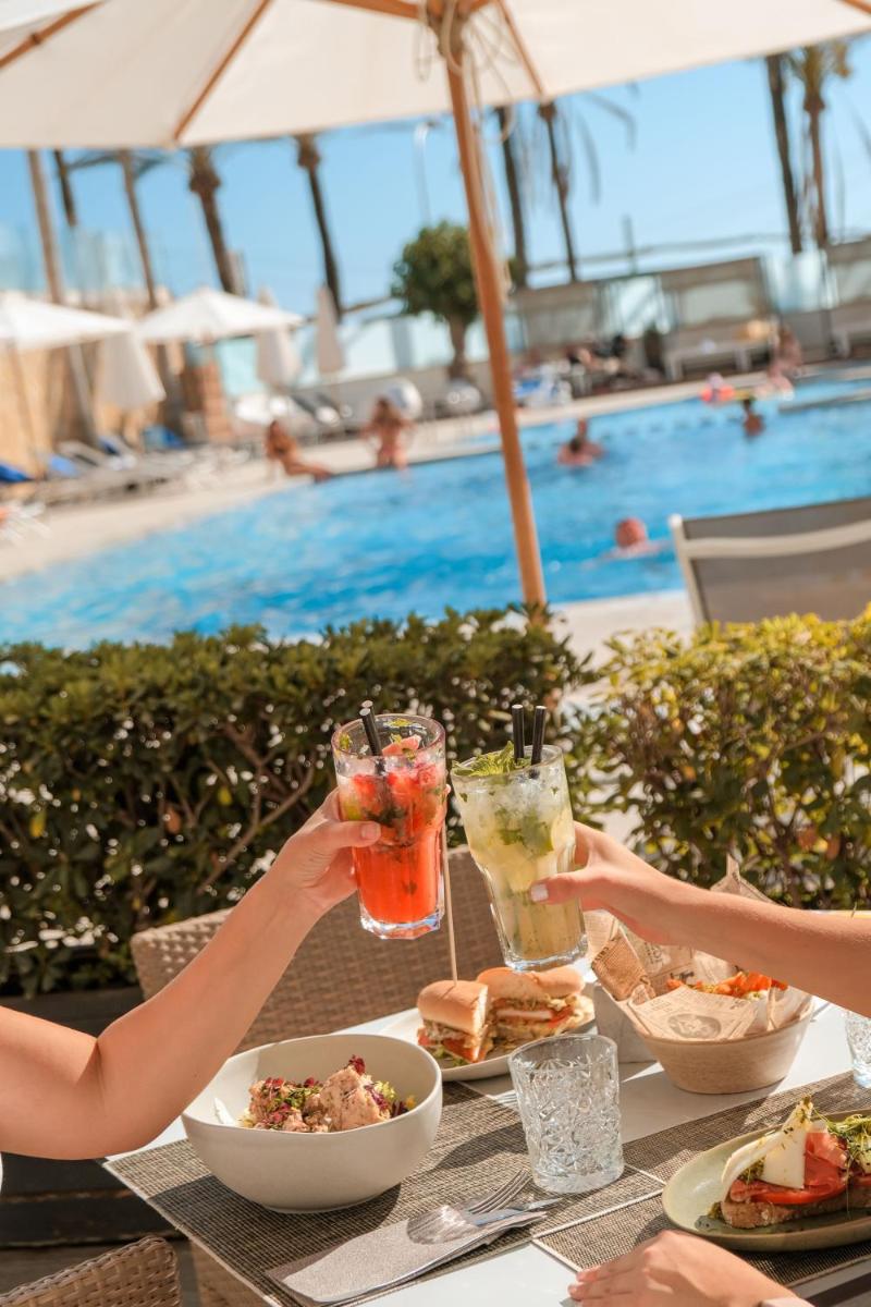 Un grupo de personas sentadas en una mesa con bebidas. en Hotel Playa Golf - Adults Only, en Playa de Palma