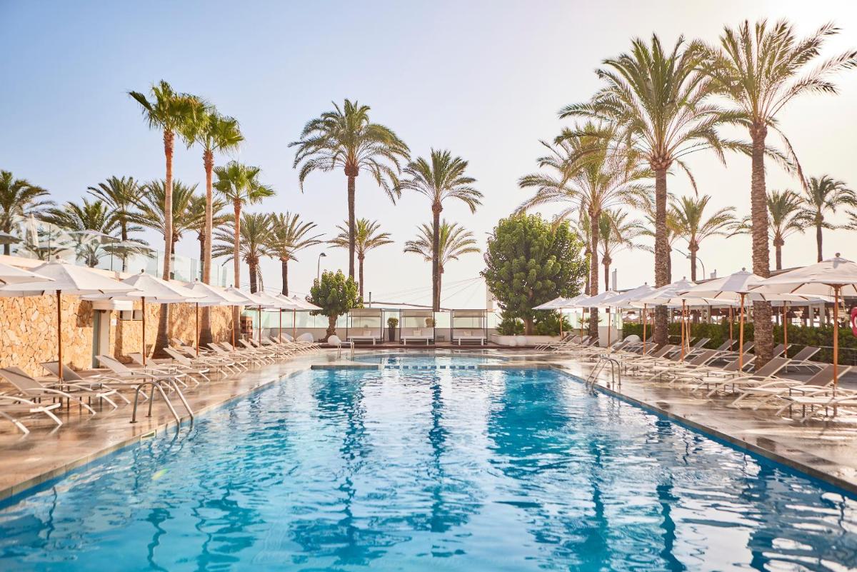 una piscina con sillas y palmeras en Hotel Playa Golf - Adults Only, en Playa de Palma