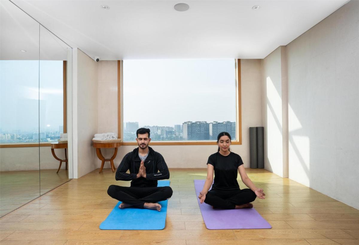 two people sitting in a yoga pose in a room at DoubleTree by Hilton-Pune Chinchwad in Pune