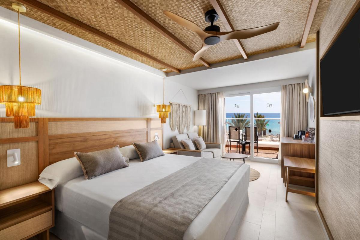 Un dormitorio con una cama y un ventilador de techo. en Hotel Riu Palace La Mola, en Playa de Migjorn