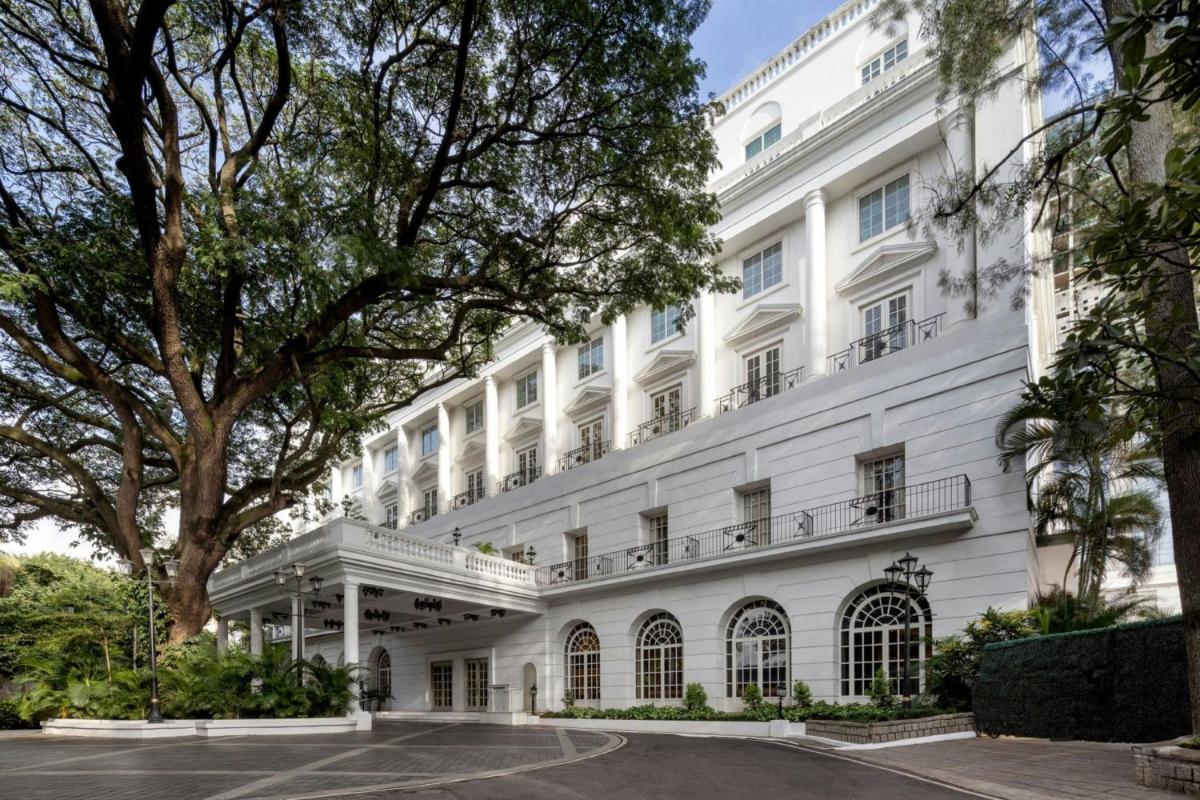 a white building with a tree in front of it at ITC Windsor, a Luxury Collection Hotel, Bengaluru in Bengaluru a white building with a tree in front of it at ITC Windsor, a Luxury Collection Hotel, Bengaluru in Bengaluru