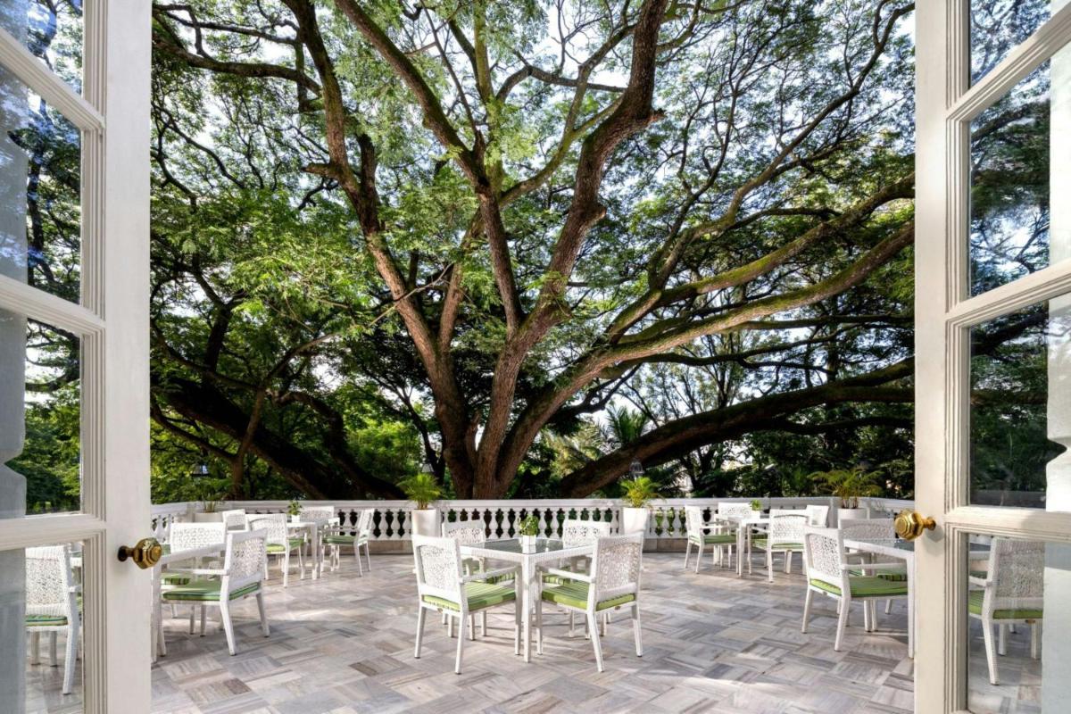 a group of tables and chairs in front of a tree at ITC Windsor, a Luxury Collection Hotel, Bengaluru in Bengaluru a group of tables and chairs in front of a tree at ITC Windsor, a Luxury Collection Hotel, Bengaluru in Bengaluru