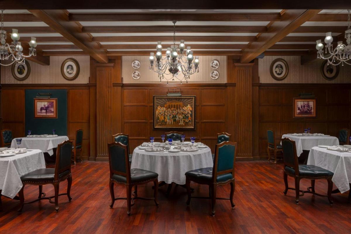 a dining room with tables and chairs and a chandelier at ITC Windsor, a Luxury Collection Hotel, Bengaluru in Bengaluru a dining room with tables and chairs and a chandelier at ITC Windsor, a Luxury Collection Hotel, Bengaluru in Bengaluru
