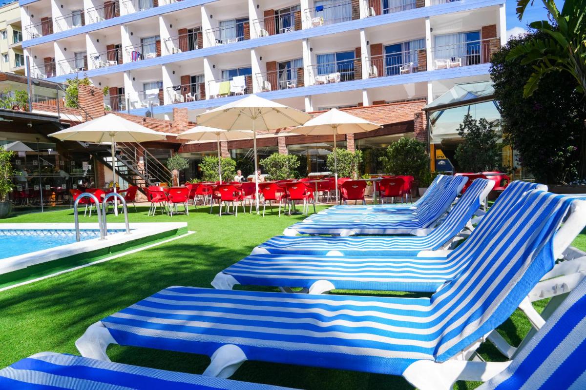 Una fila de sillones azules y blancos junto a una piscina. en htop Palm Beach & SPA #htopEnjoy, en Lloret de Mar