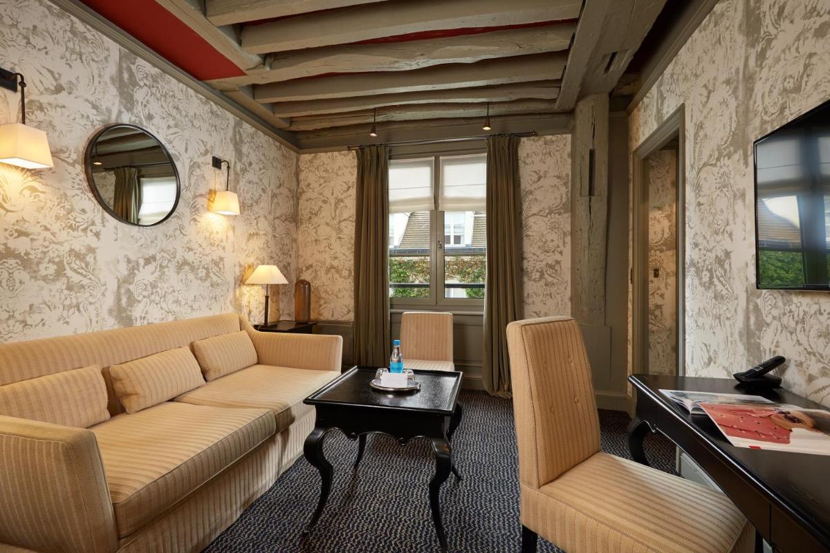 un salon avec un canapé et une table dans l'établissement Le Pavillon de la Reine & Spa, Place des Vosges, à Paris