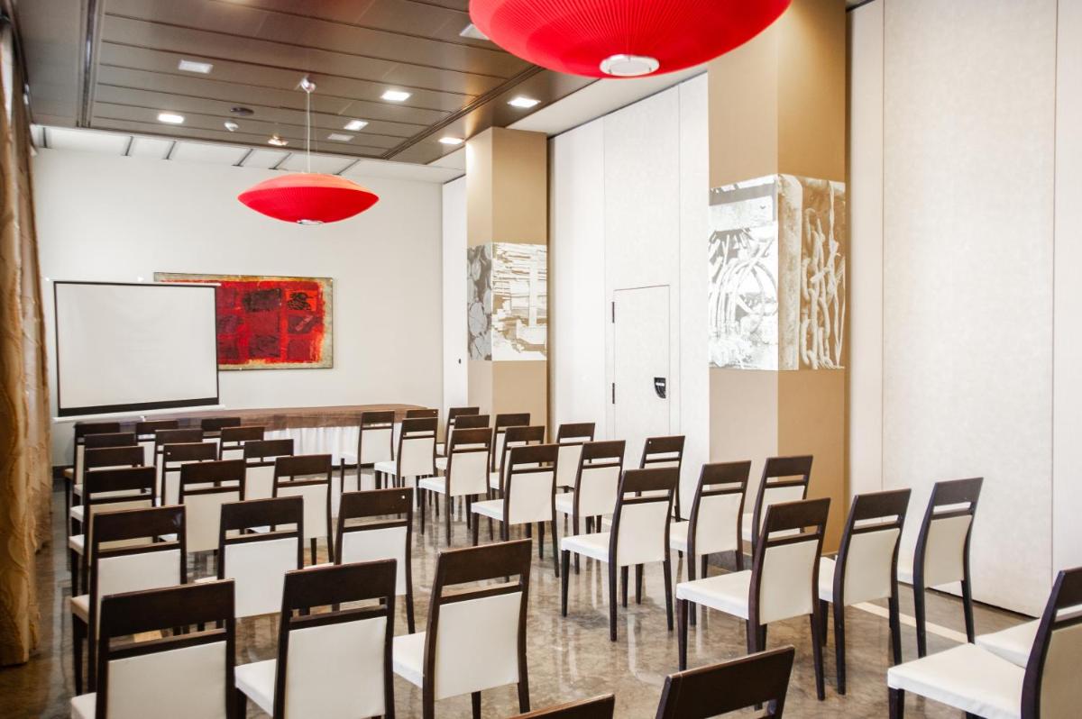 una sala de conferencias con sillas y una pantalla de proyección en AZZ Asturias LangreHotel & Spa, en Langreo