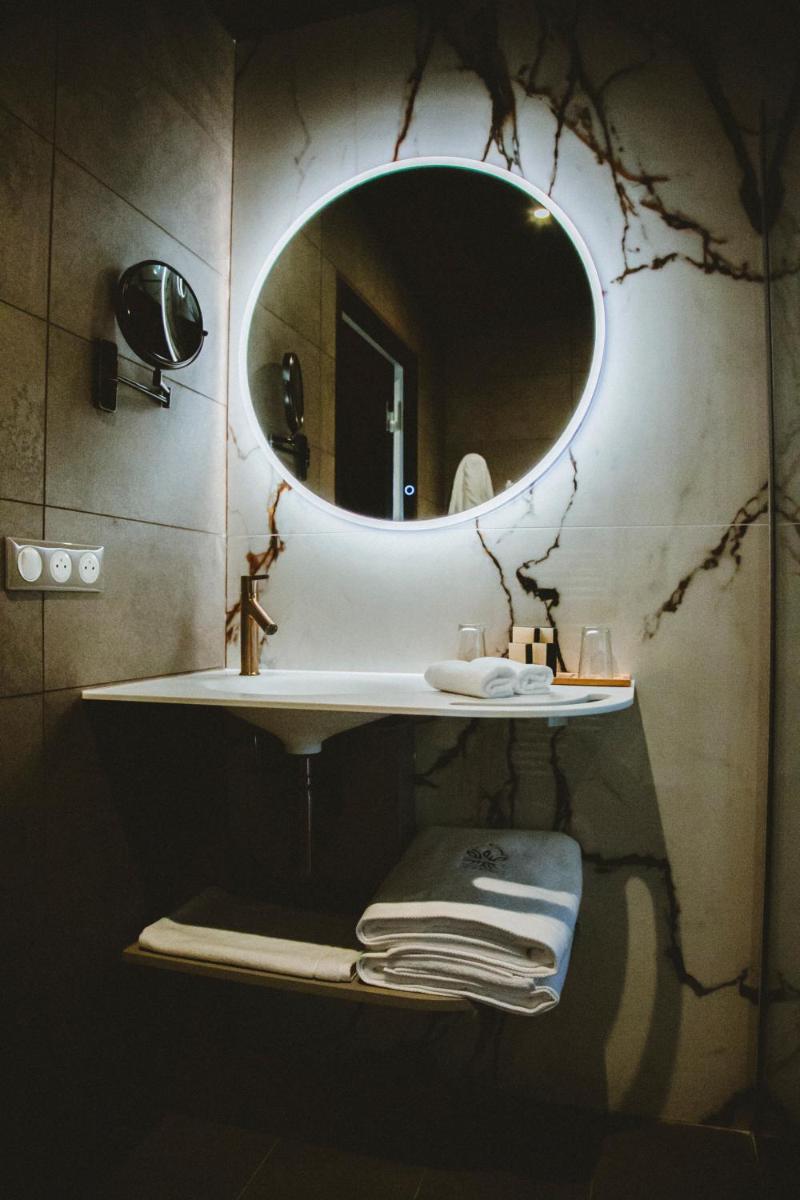 La salle de bains est pourvue d'un miroir et d'une étagère avec des serviettes. dans l'établissement Le Berceau de La Source, à Bagnères-de-Bigorre