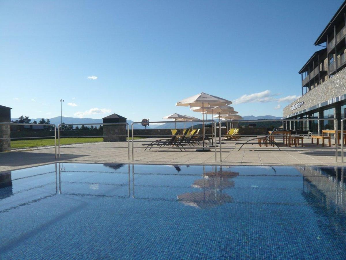 Una piscina con sillas y sombrillas al lado de un edificio. en HG La Molina, en La Molina