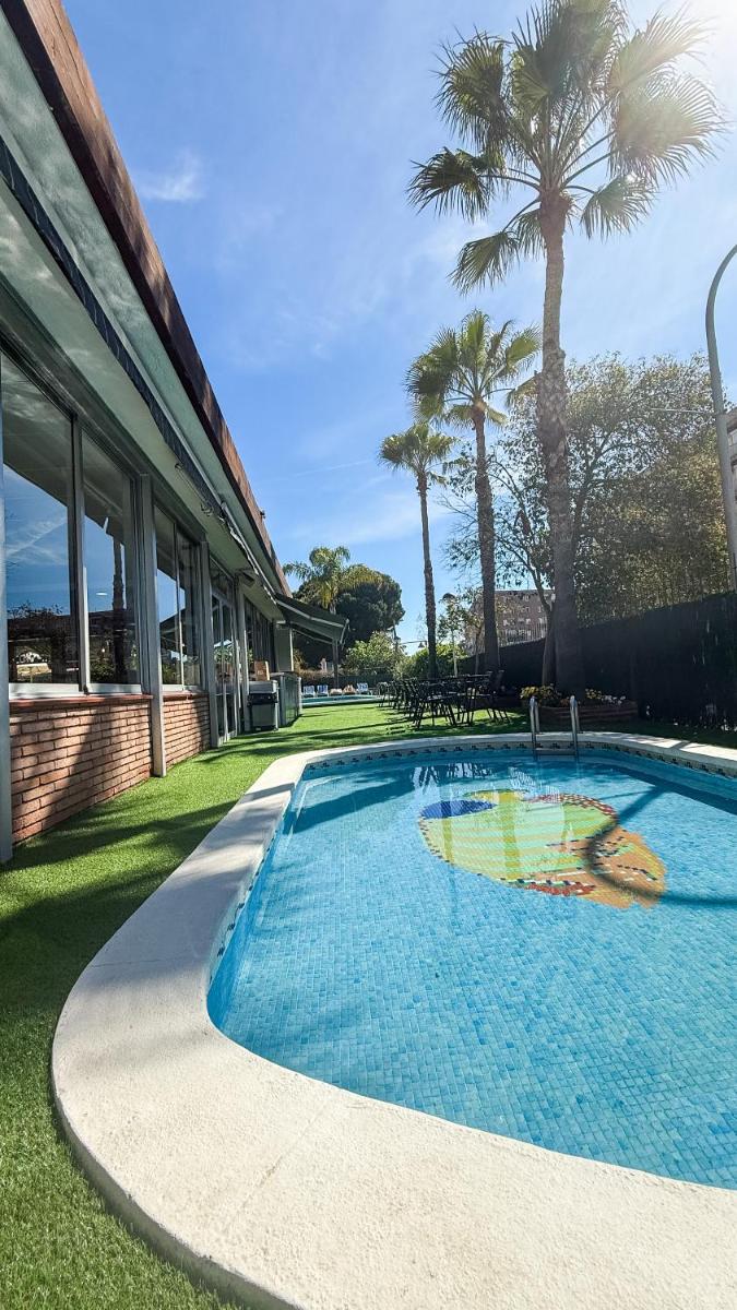 una piscina frente a una casa con palmeras en htop Palm Beach & SPA #htopEnjoy, en Lloret de Mar
