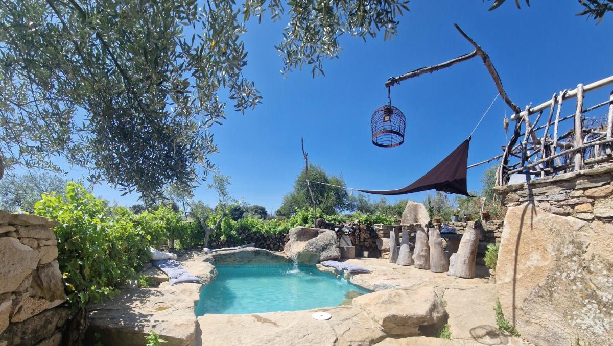 una piscina en un jardín con una pared de roca en Orgullo Rural, en Bermellar