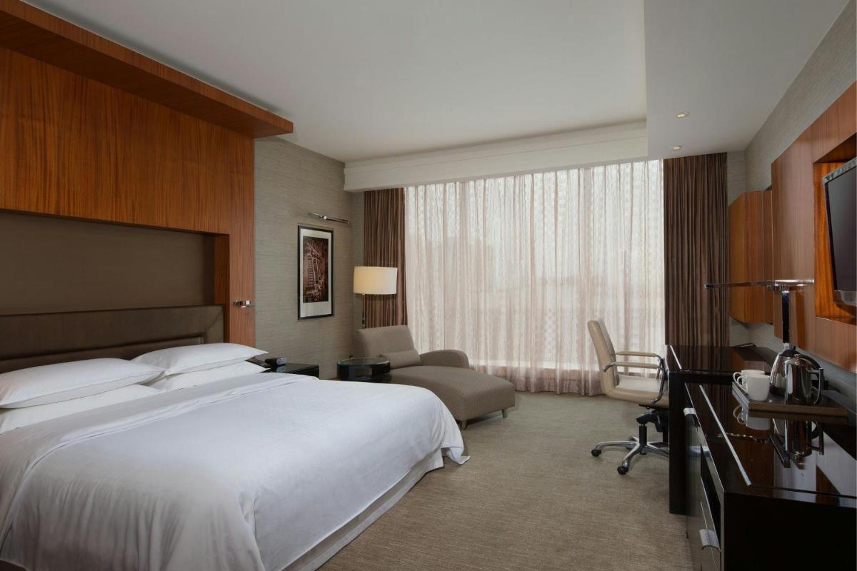 a hotel room with a large white bed and a chair at Sheraton Grand Bangalore Hotel at Brigade Gateway in Bengaluru
