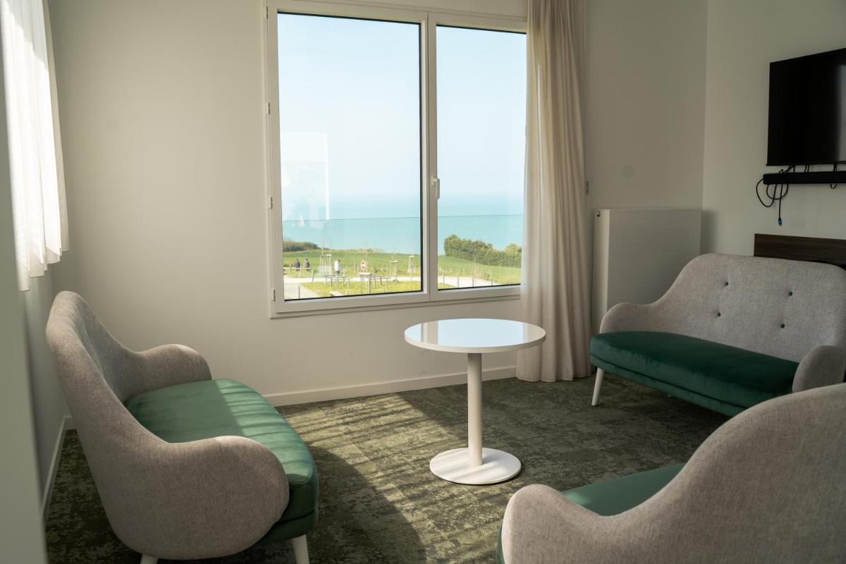 un salon avec deux chaises, une table et une fenêtre dans l'établissement Hôtel Le Manoir du Roselier, à Plérin